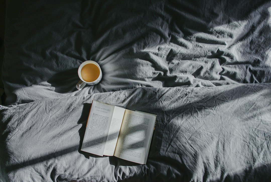 Livre ouvert et tasse de thé sur une couverture.