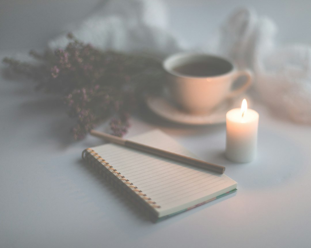 Carnet ouvert, bougie et tasse pour un moment d’écriture.